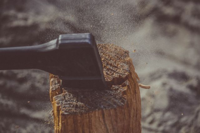 Axe striking a tree stump, sending wood chips flying